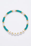 Teal JOYFUL beaded bracelet with gold-colored spacers on a soft-white background