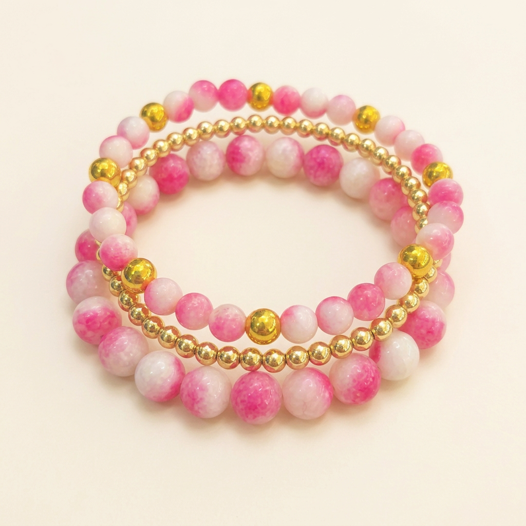 Tourmaline pink jade three-bracelet set arranged in a stack on a warm ivory background