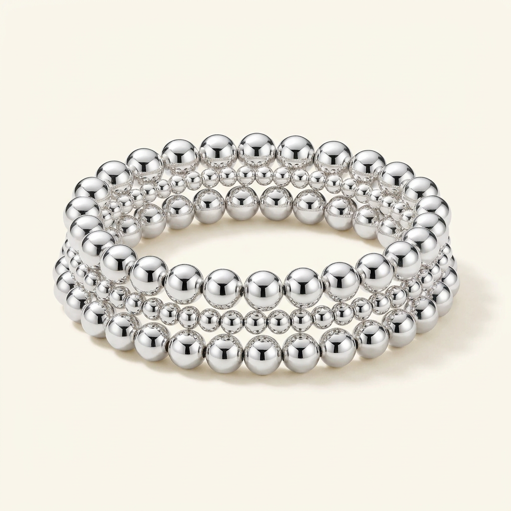 Stack of three handmade silver-plated beaded bracelets on an ivory background