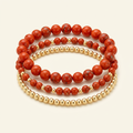 Handmade red jasper and gold-plated three-bracelet stack on a warm ivory background