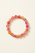 Pink, orange, and golden-toned glass bead bracelet with spacers on an off-white background