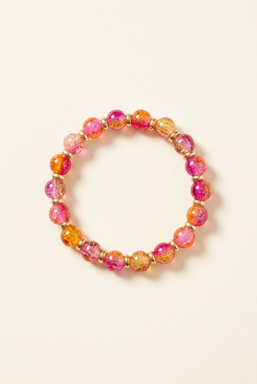 Pink, orange, and golden-toned glass bead bracelet with spacers on an off-white background