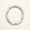 Handmade howlite bead bracelet with silver-colored spacers on a warm ivory background