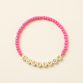 Pink Survivor handmade seed bead bracelet with cream letter beads on an ivory background