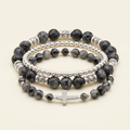 Black larvikite and silver-colored three-bracelet stack with a silver cross on an ivory background