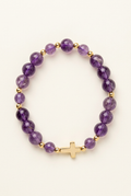 Purple amethyst bracelet lying flat on an ivory background with gold colored spacers and the gold colored cross facing the camera