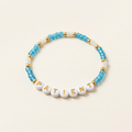 Patient bracelet with blue and white beads and gold-tone accents on an ivory background
