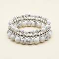 Handmade howlite and silver-plated three-bracelet stack on a warm ivory background