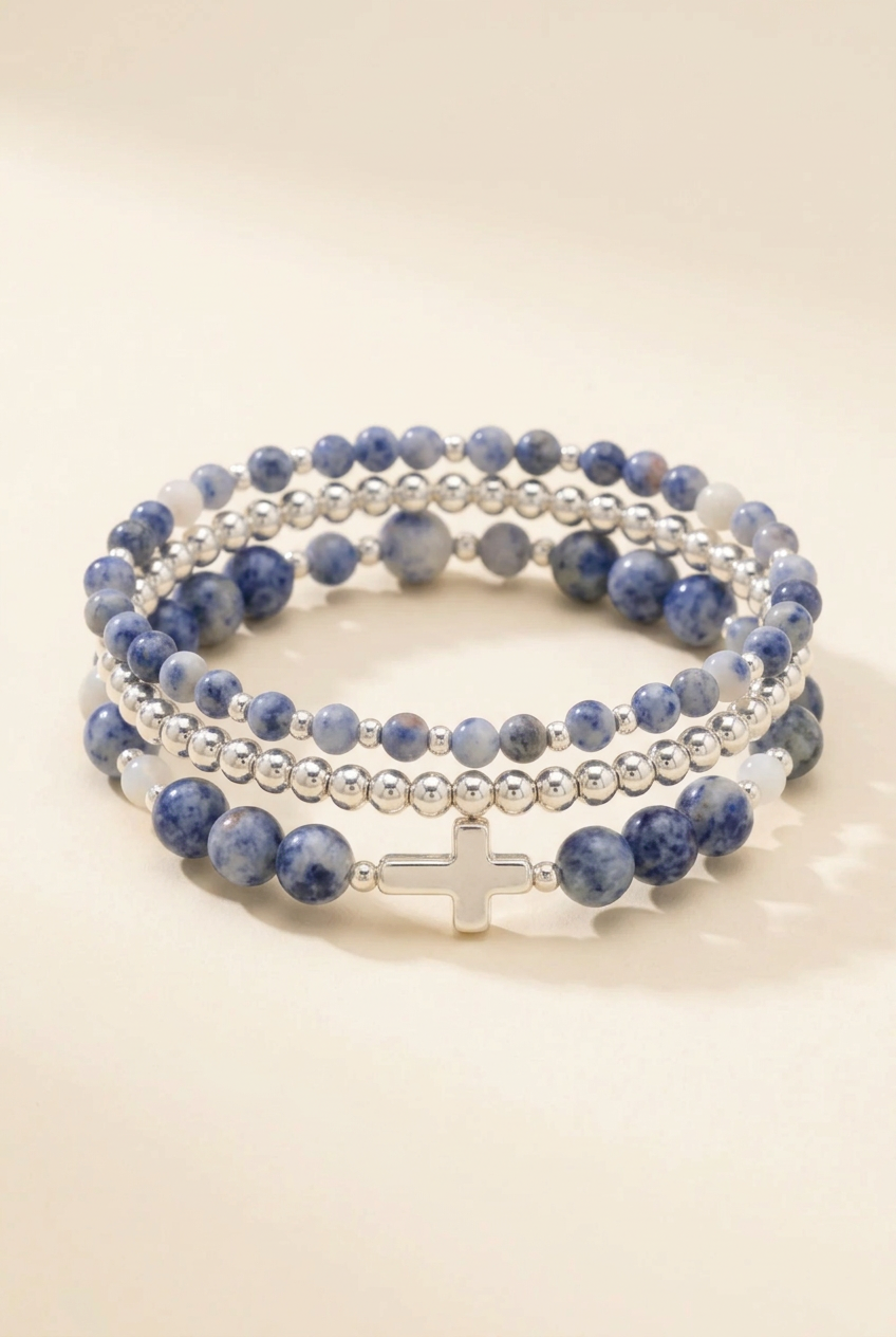 Walk by Faith Blue Spot Jasper three-bracelet set stacked on a warm ivory background with the silver cross at the front