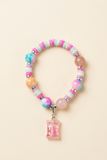 Pastel children's beaded bracelet with a Sweet Treats charm on a warm ivory background
