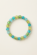 Blue and green glass bead bracelet with shimmering spacers on an off-white background