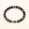 Handmade black larvikite cross bracelet on a warm ivory background