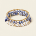 Handmade blue spot Jasper and gold-plated three-bracelet stack with JUST BREATH lettering on an ivory background