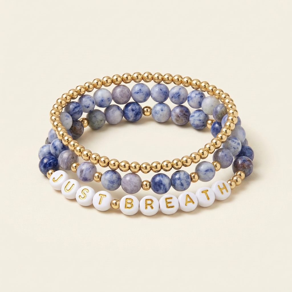 Handmade blue spot Jasper and gold-plated three-bracelet stack with JUST BREATH lettering on an ivory background