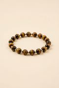 Tiger eye bead bracelet with gold-plated spacers on a warm ivory background