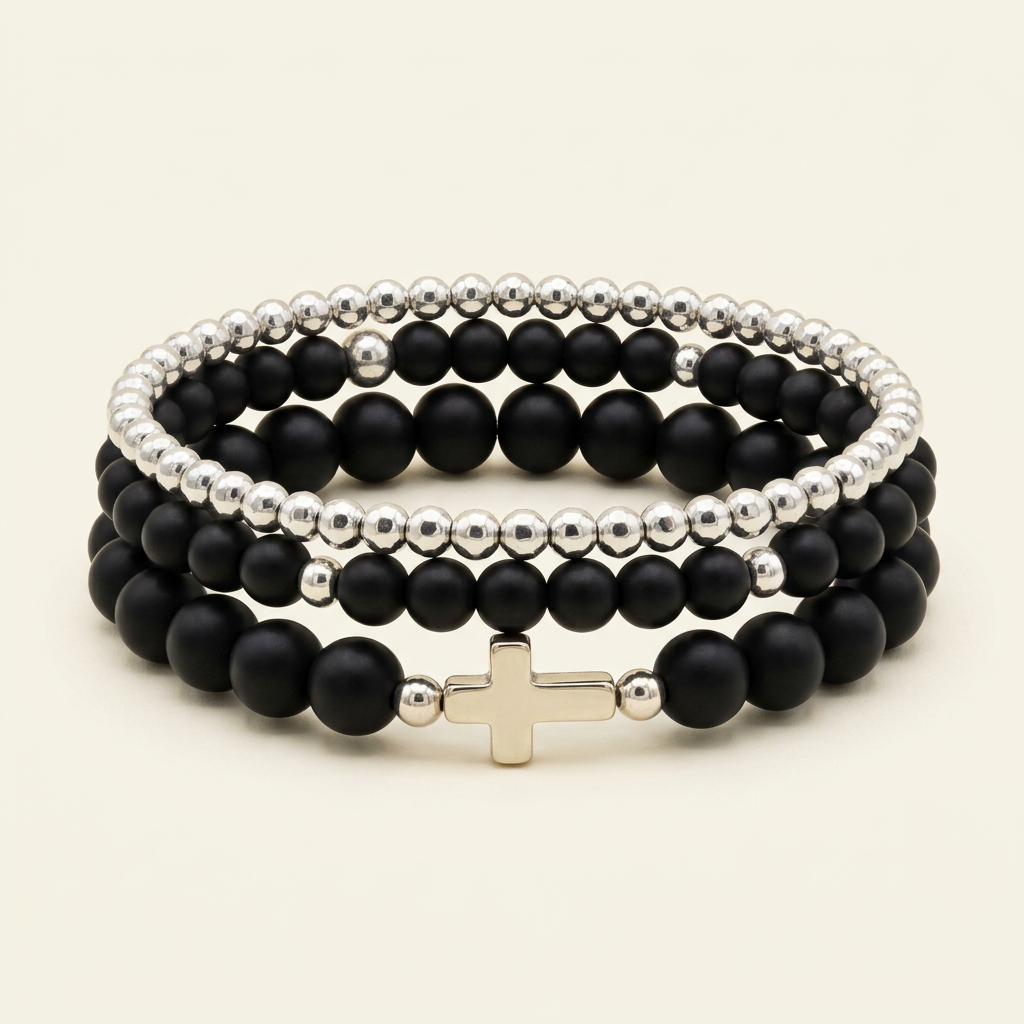 Three black onyx and silver-toned bracelets stacked on a warm ivory background