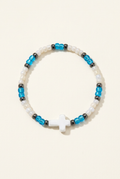 White and bright blue seed bead bracelet with a silver cross on an ivory background
