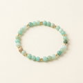 Handmade amazonite bracelet with gold-plated spacers on a warm ivory background