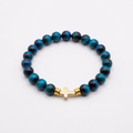 Aquamarine tiger eye bracelet with a gold-colored sideways cross on a white background