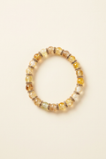Yellow, amber, and clear glass bead bracelet with spacers on an off-white background
