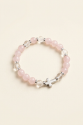 Rose quartz and clear quartz bracelet with silver-colored spacers and cross on an ivory background