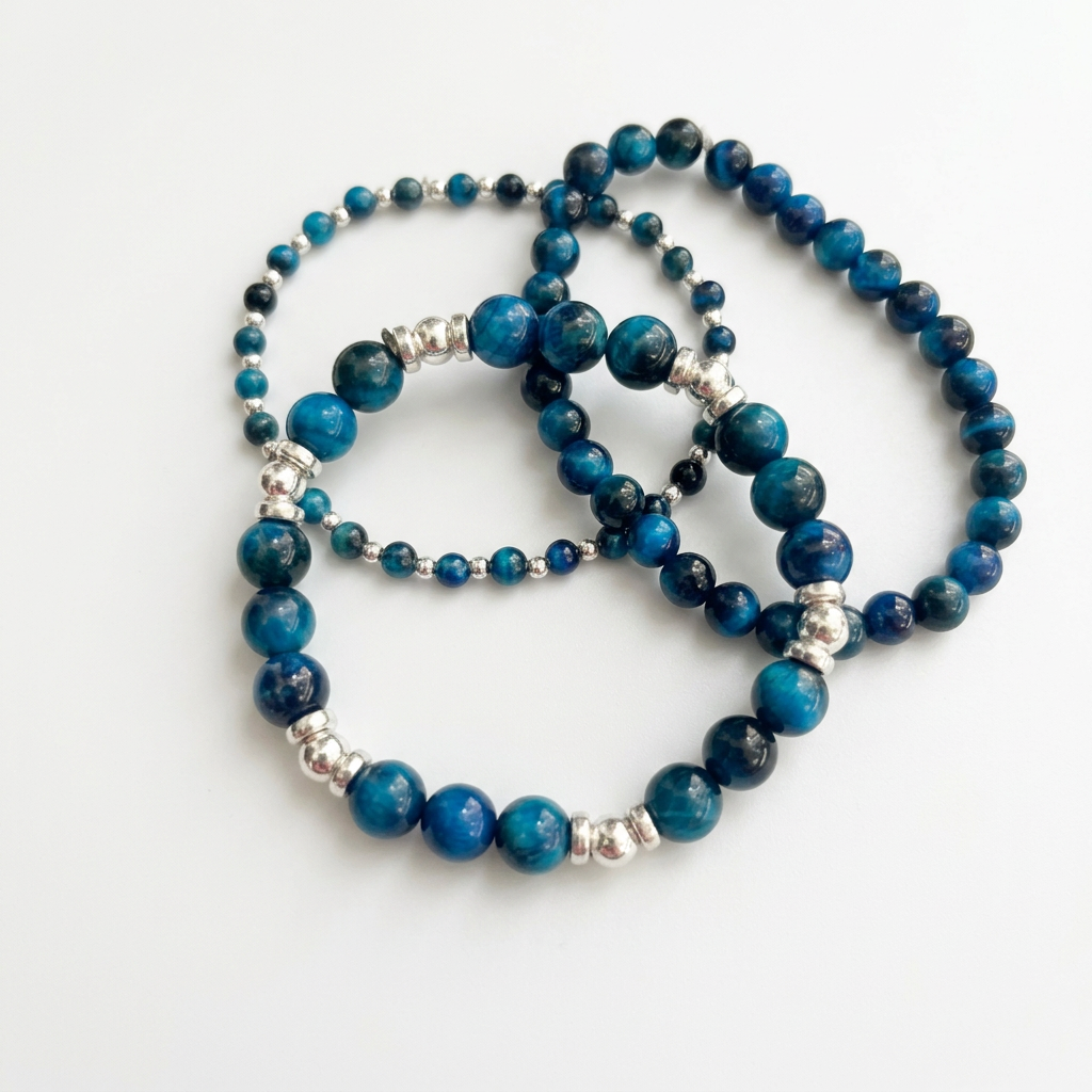 Three blue aquamarine bracelets with silver spacers on a white background