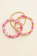 Three-piece watermelon pink jade and gold-plated bracelet set on an ivory background