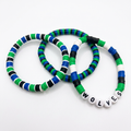Three green, blue, black, and white beaded bracelets, one with WOLVES letter beads, on a white background.