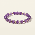 Purple amethyst bead bracelet with gold-plated spacers on a warm-white background