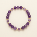 Purple amethyst bracelet with gold-plated spacers arranged in a circle on an ivory background