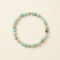 Handmade smooth amazonite bracelet with gold-plated spacers arranged in a circle on a warm ivory background