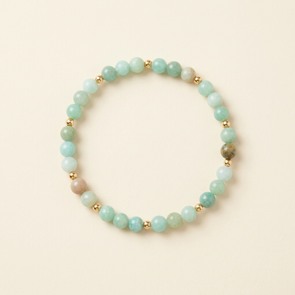 Handmade smooth amazonite bracelet with gold-plated spacers arranged in a circle on a warm ivory background
