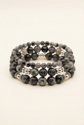 Handmade three-bracelet stack with silver-plated accents on a warm ivory background