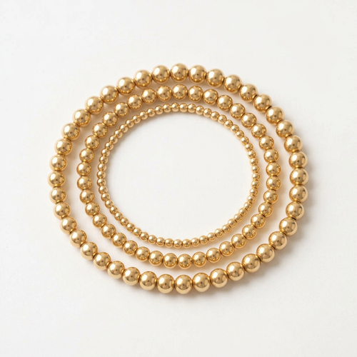 Three gold-plated beaded bracelets displayed without a hand on a clean white background