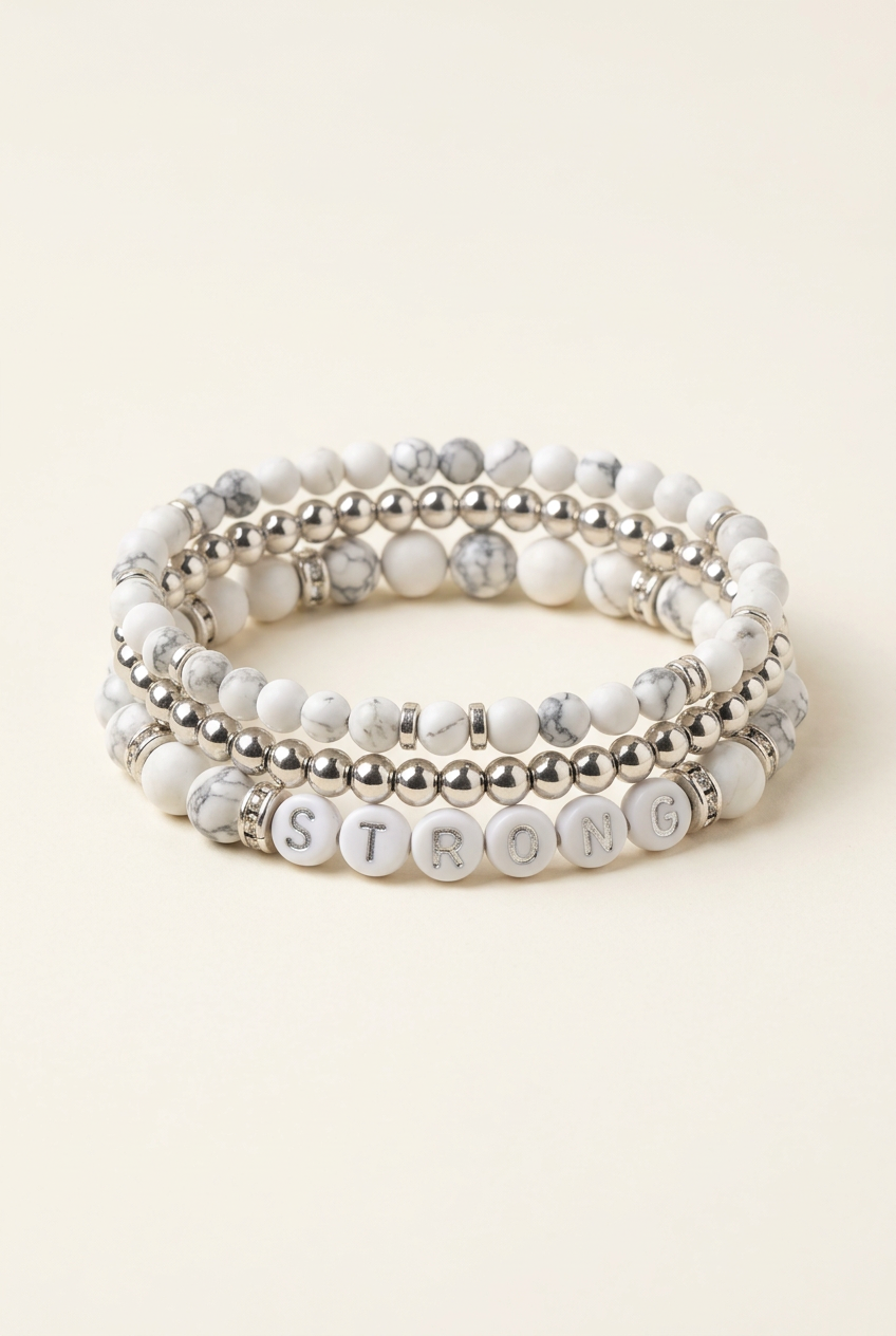Handmade STRONG howlite and silver-plated three-bracelet stack on a warm ivory background