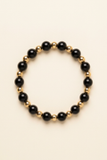 Black onyx and gold-plated bead bracelet on a warm ivory background