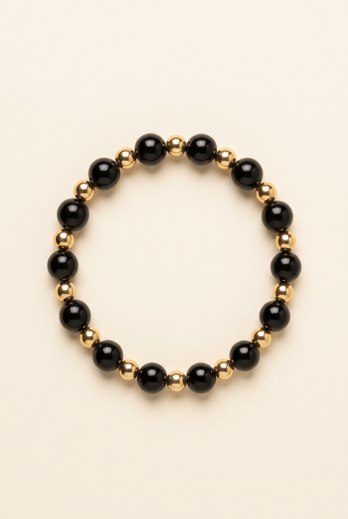 Black onyx and gold-plated bead bracelet on a warm ivory background
