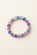 Blue, pink, and purple glass bead bracelet with spacers on an off-white background